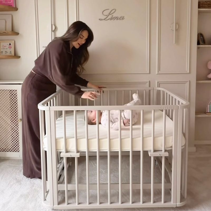 nieuwe mama in babykamer met beige ledikant babyrace, beige babykamer, beige babybed, beige babywieg